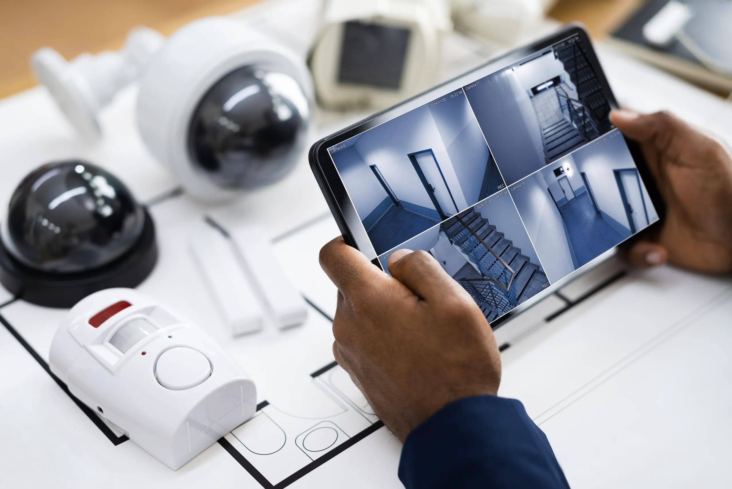 Użytkownik sprawdza widok z kamer IP na tablecie, analizując system monitoringu