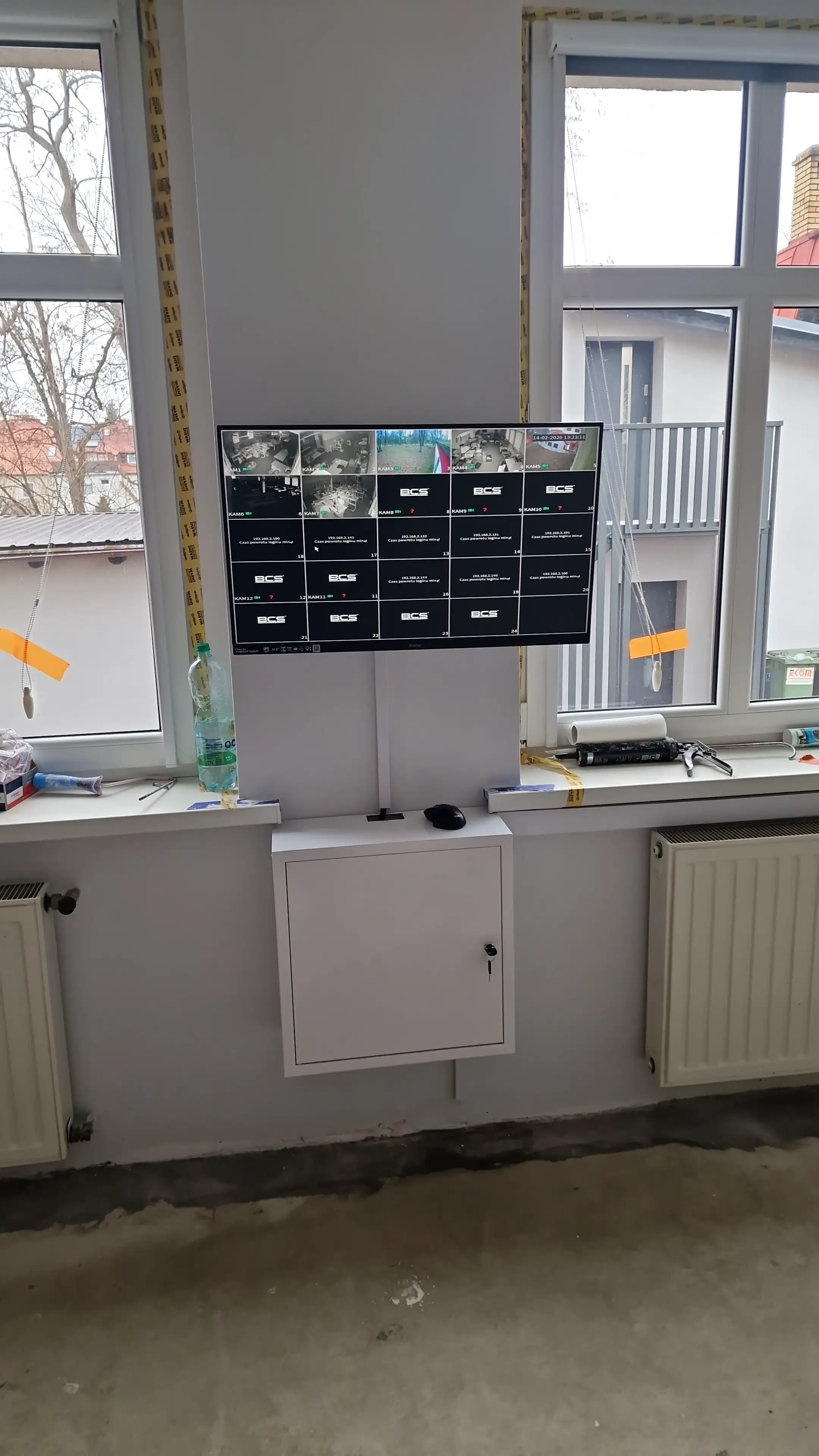 Monitor z systemem monitoringu na tle okna, przymocowany na ścianie