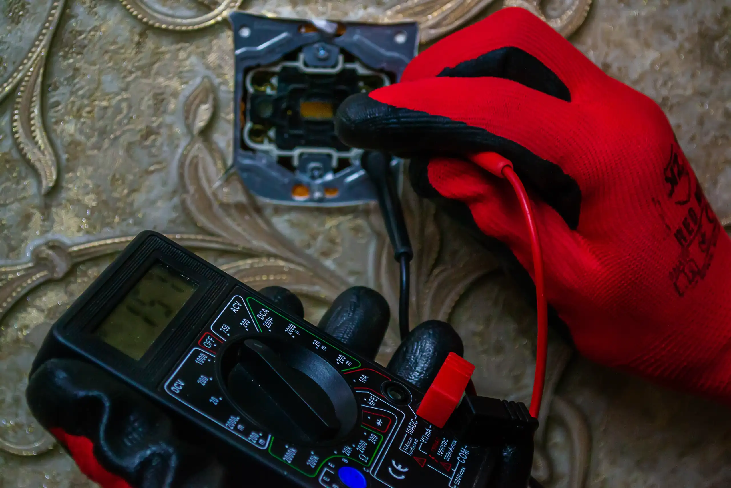 Pomiar napięcia za pomocą multimetru przy instalacji elektrycznej na ścianie