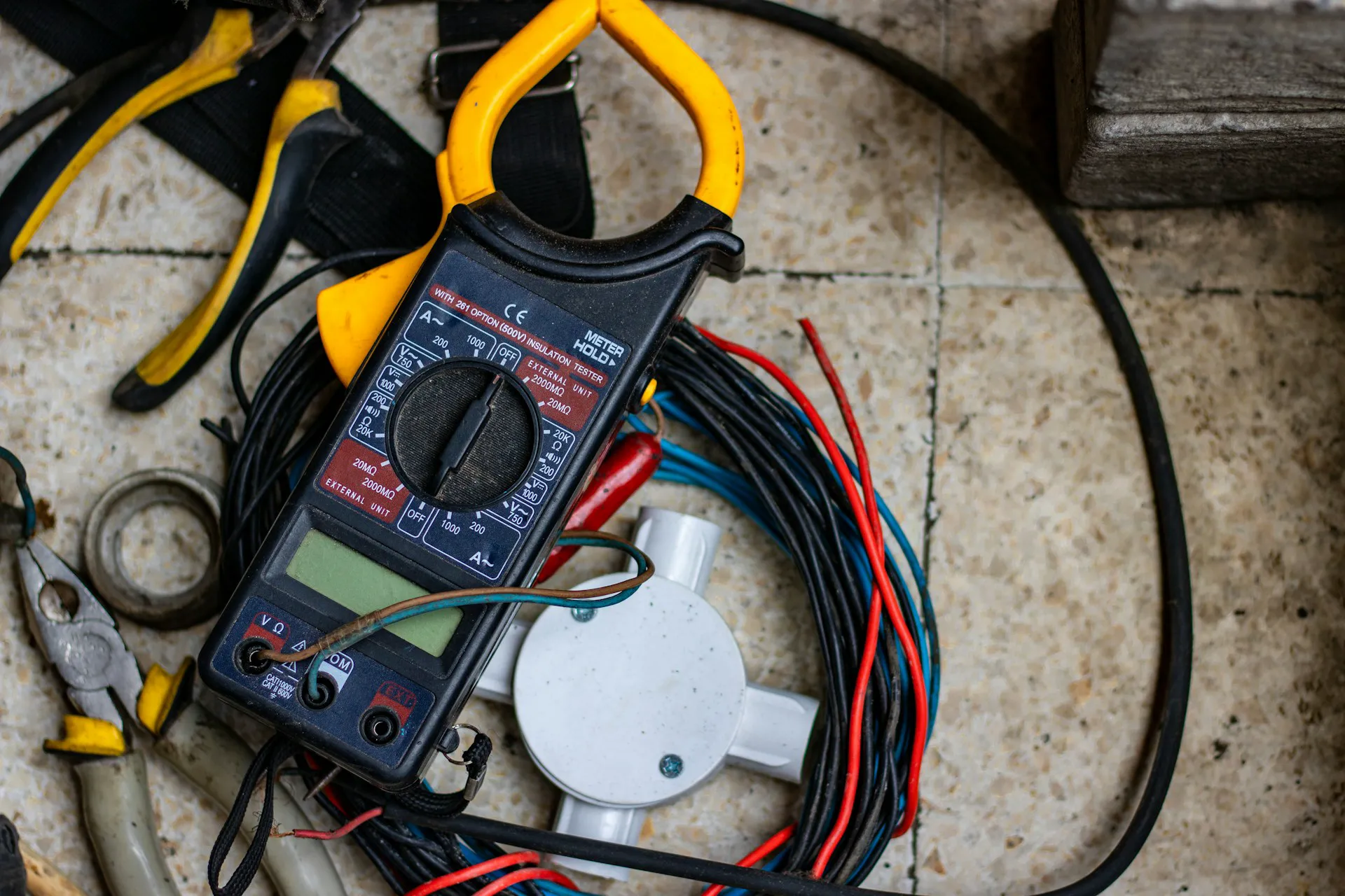 Miernik elektryczny na tle przewodów i narzędzi, idealny do usług pomiarów elektrycznych