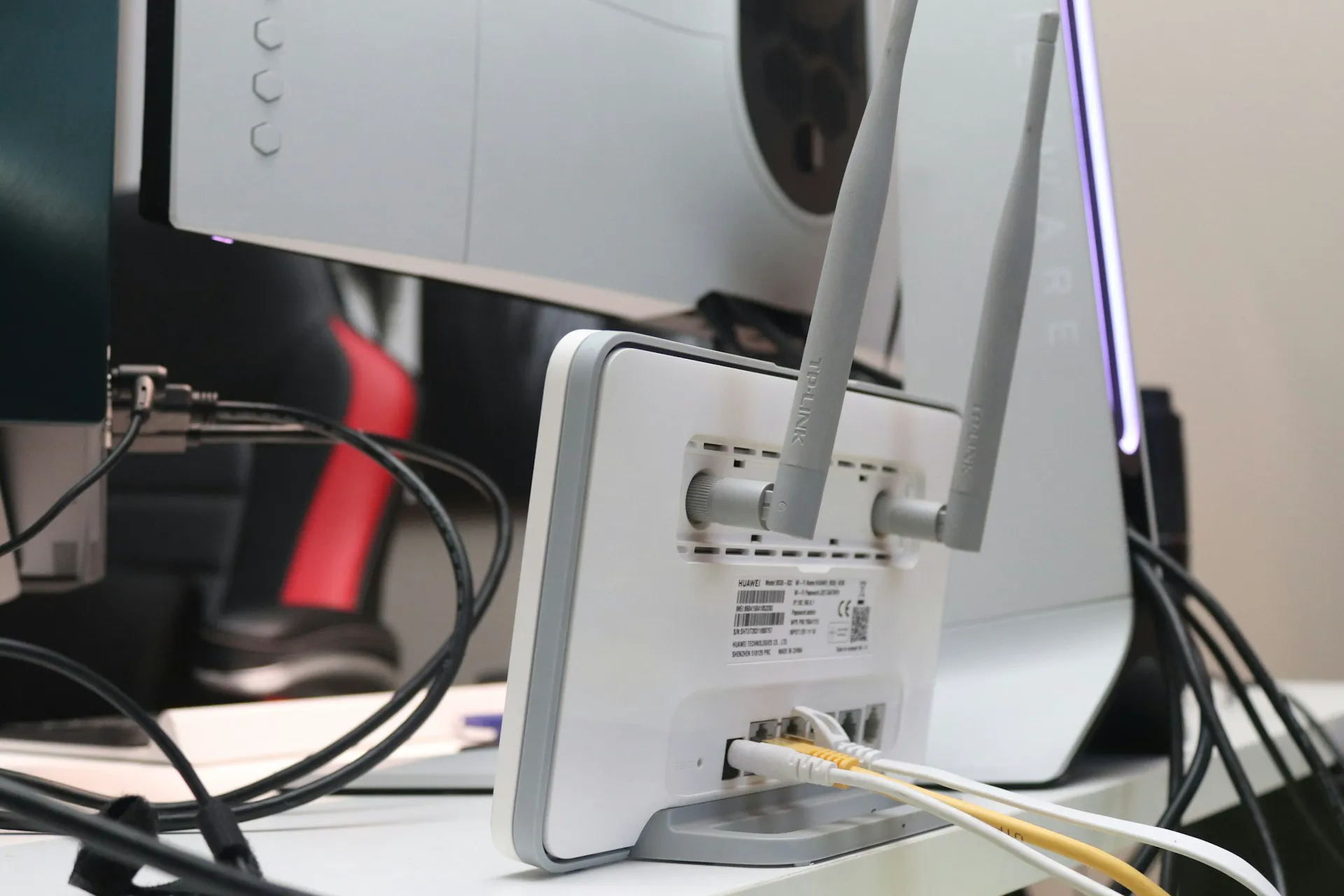 Router bezprzewodowy z antenami oraz podłączonymi kablami ethernetowymi na biurku