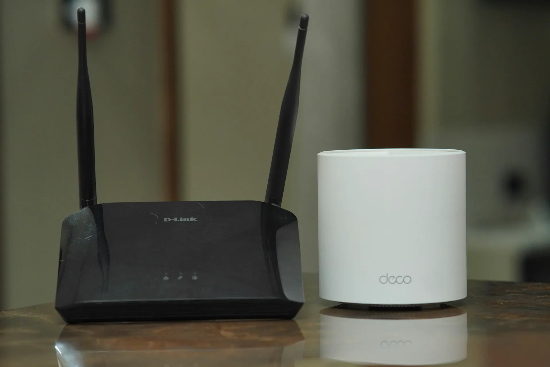 Router D-Link oraz urządzenie Deco na stole, pokazujące rozwiązania sieci LAN i WiFi