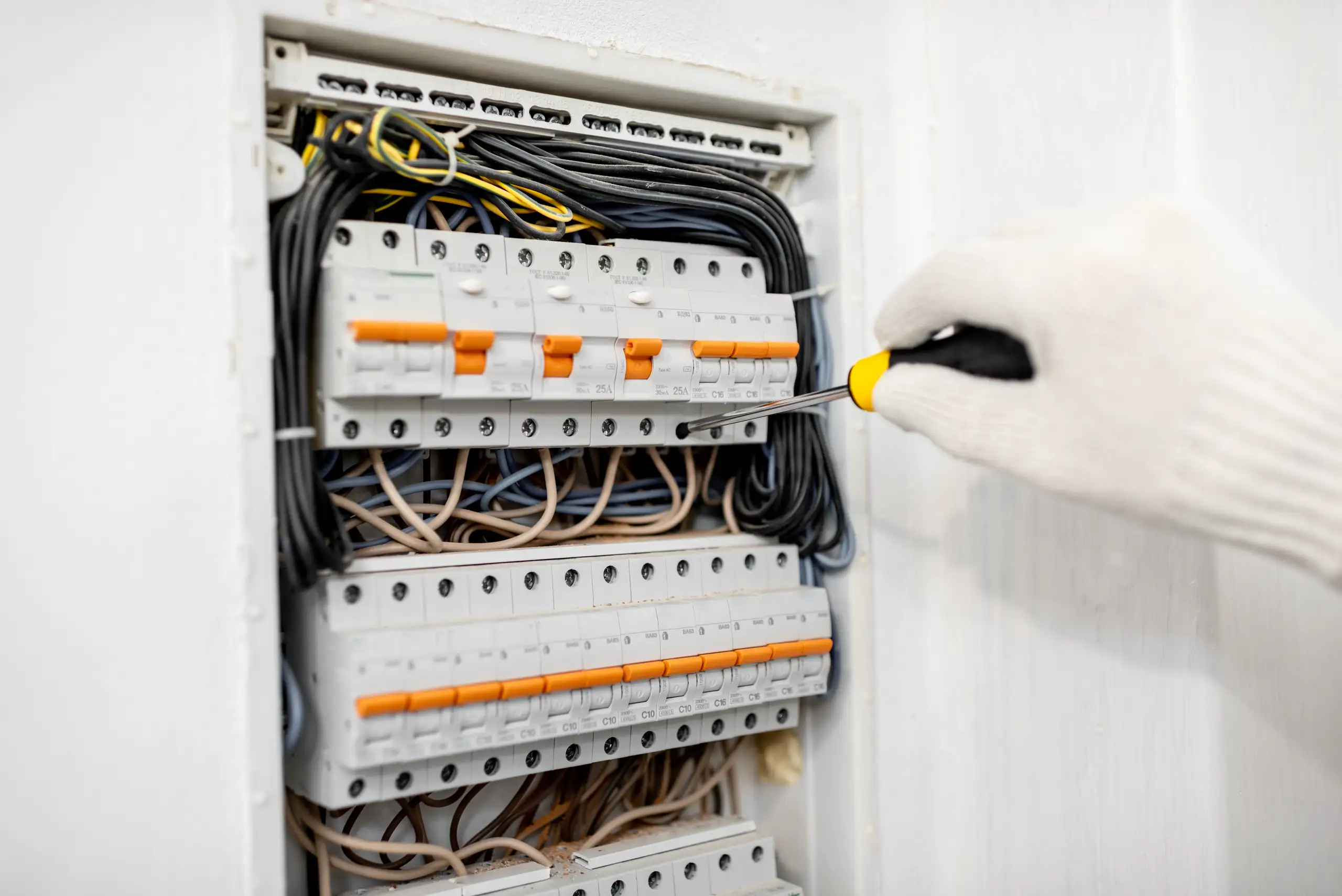 Pracownik wykonujący modernizację instalacji elektrycznej w rozdzielnicy elektrycznej
